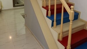 Una escalera con peldaños en rojo y azul alternados, barandillas de madera y una baranda.