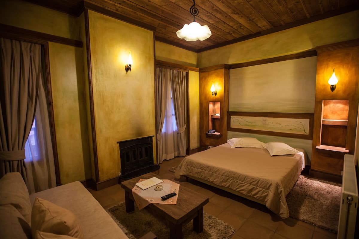 Ein Hotelzimmer mit einem Bett, einer Couch, einem Holztisch und zwei Wandlampen.
