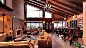 Un'ampia zona relax con camino, sedute confortevoli e un'area bar con tavoli e sedie in legno.