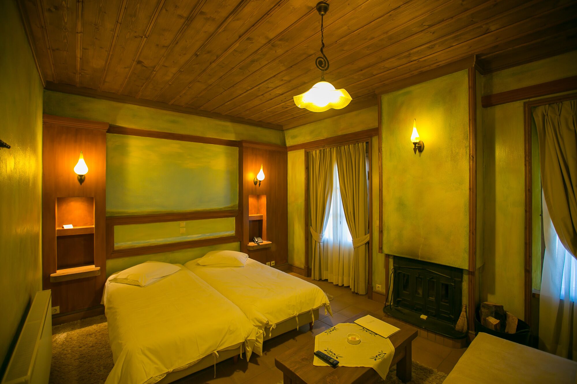 A hotel room with two beds, a fireplace, and wall-mounted lamps.