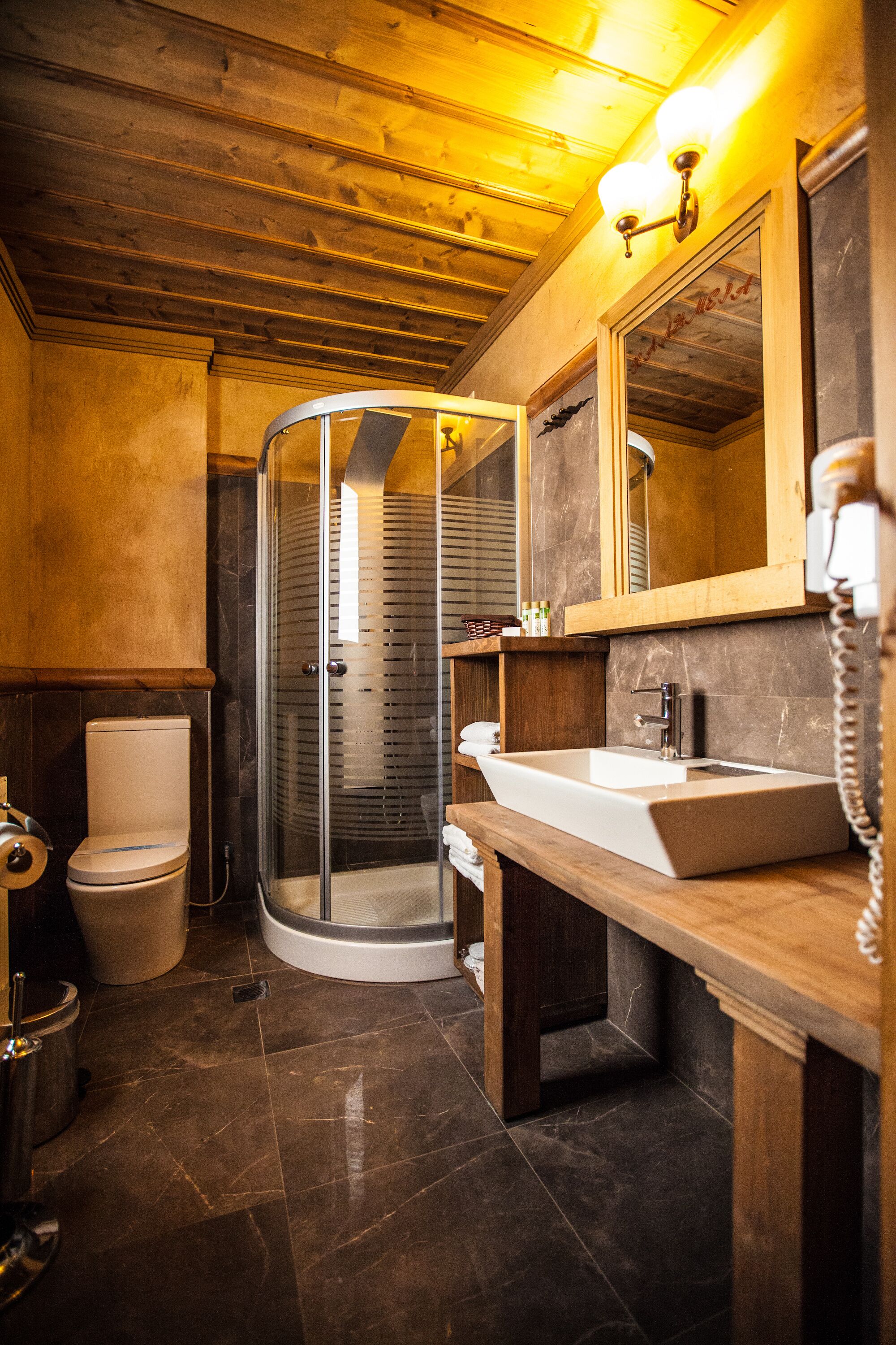 A bathroom with a glass shower enclosure, a white sink, and a wooden vanity.