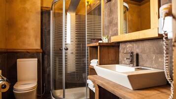 A bathroom with a glass shower enclosure, a white sink, and a wooden vanity.