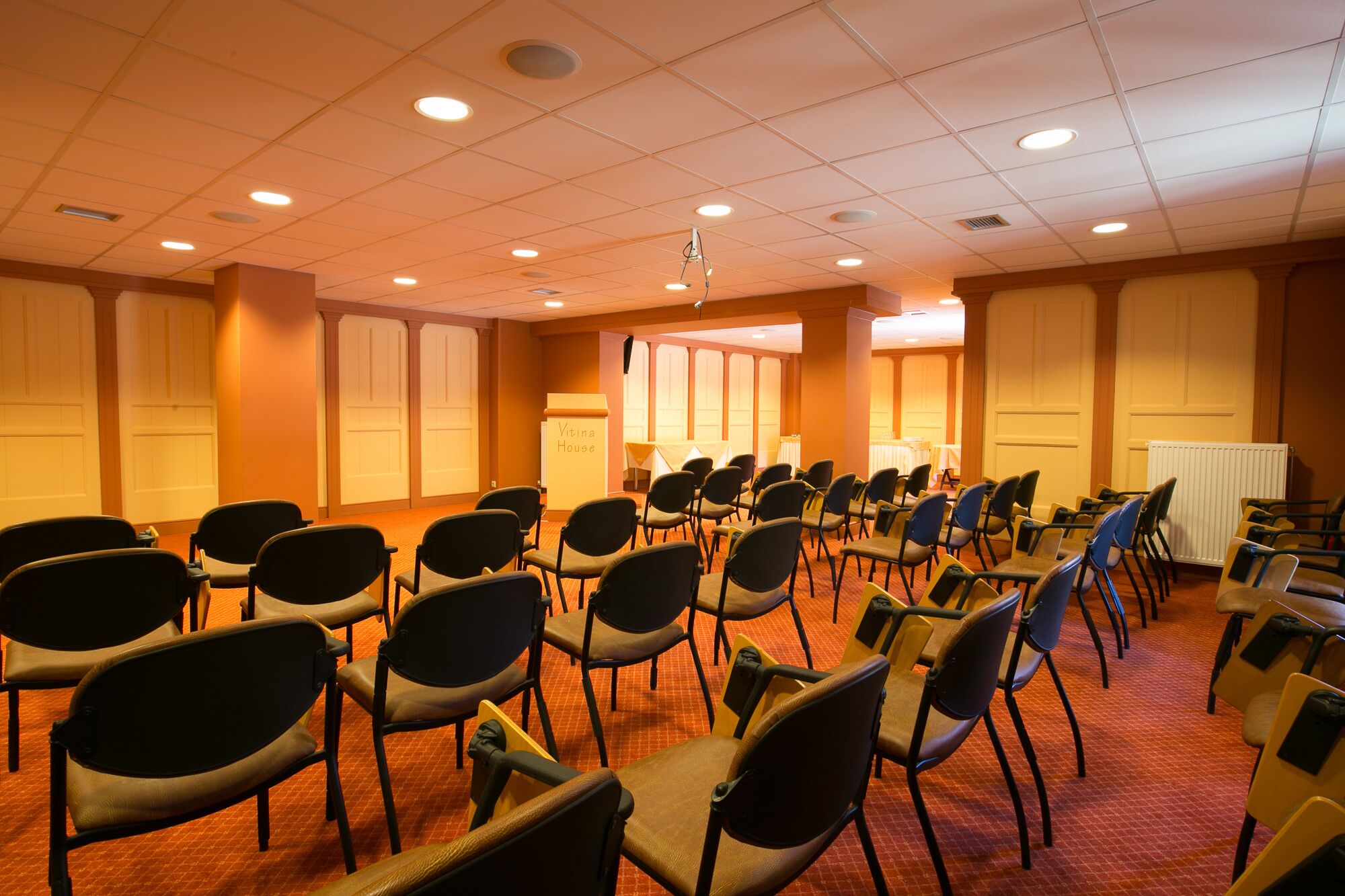 A conference room with rows of chairs, a podium, and a whiteboard.
