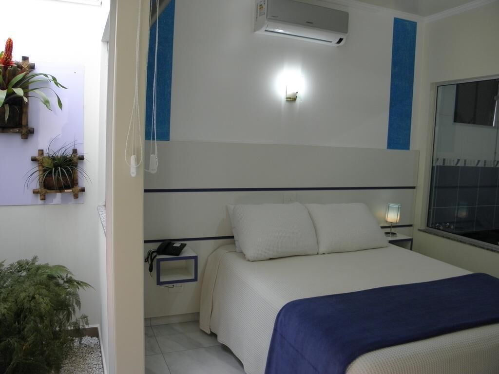 Une chambre à coucher comprenant un lit, une table de chevet, une lampe, un appareil de climatisation et des plantes fixées au mur.