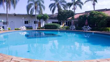 Una piscina rodeada de palmeras y sillas de descanso.