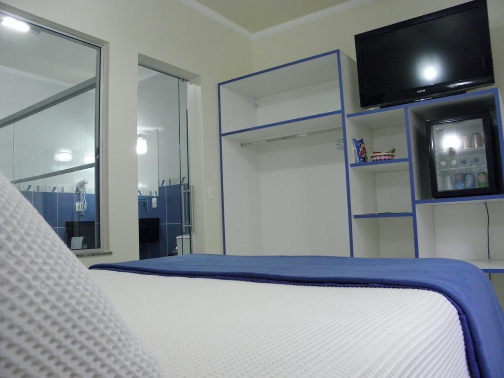 Une chambre avec un lit, une télévision, une armoire et un petit réfrigérateur.