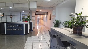 A hotel reception area with a reception desk labeled "RIO CLARO Plaza Hotel," a clock, and several potted plants. - Rio Claro Plaza Hotel (Rio Claro)