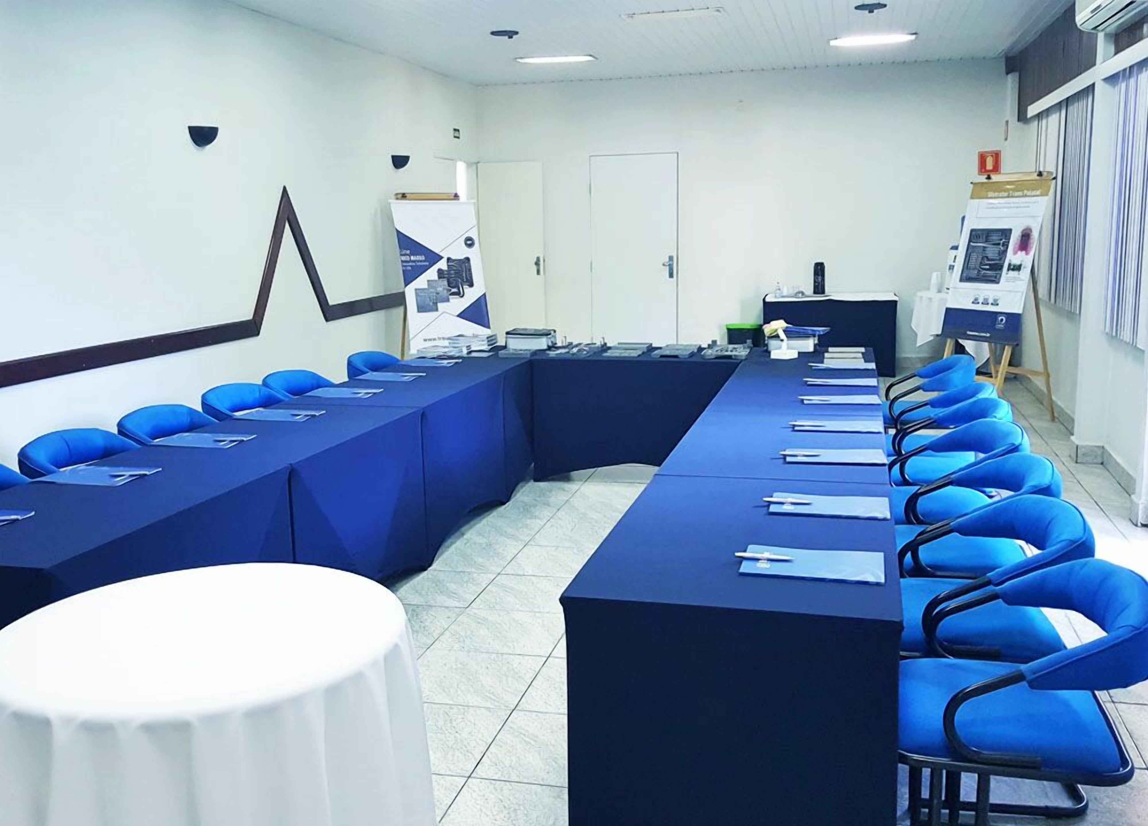 A conference room with a long table, blue chairs, and a white table at the front.
