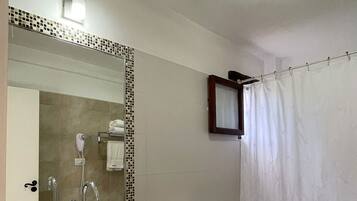 Un baño con lavamanos, espejo, inodoro y cortina de ducha.