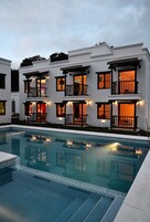 Un edificio de varios pisos con balcones y una piscina delantera.