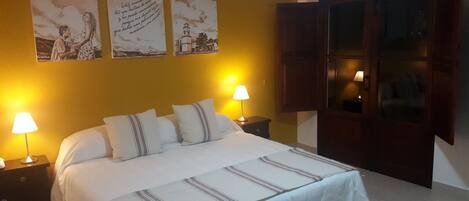 A hotel room with a bed, two bedside lamps, a nightstand, and a wooden wardrobe.