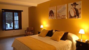 A hotel room with a large bed, two bedside lamps, a chair, and artwork on the wall.