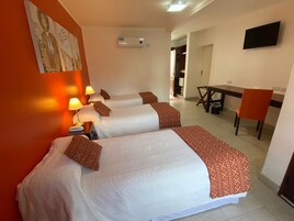 A hotel room with two beds, a desk, a chair, and an air conditioning unit.
