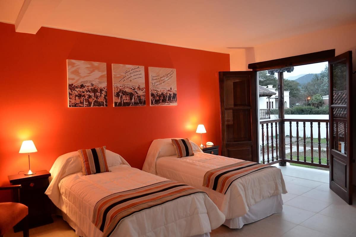 Ein Hotelzimmer mit zwei Betten, einem Balkon und Blick sowie Bildern an der Wand.