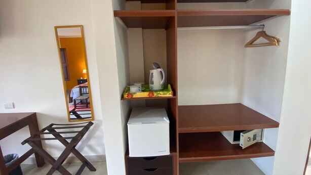 Ein Zimmer mit Holzschrank, kleinem Tisch und Kleiderstange.