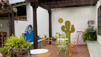 A covered patio area with wooden beams, potted plants, and outdoor furniture.