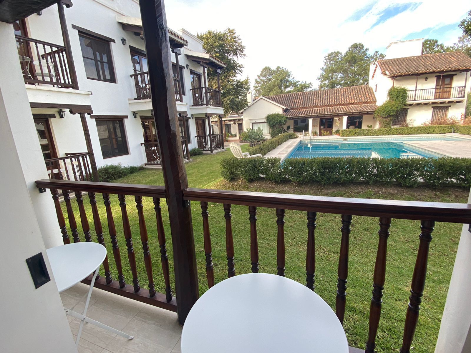 Un balcón con vistas a una piscina, un césped y edificios vecinos.