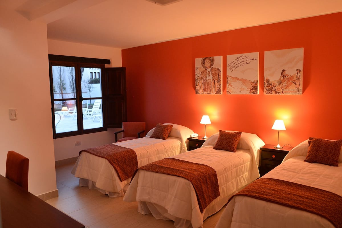 Ein Hotelzimmer mit zwei Betten, einem Fenster und Bildern an der Wand.