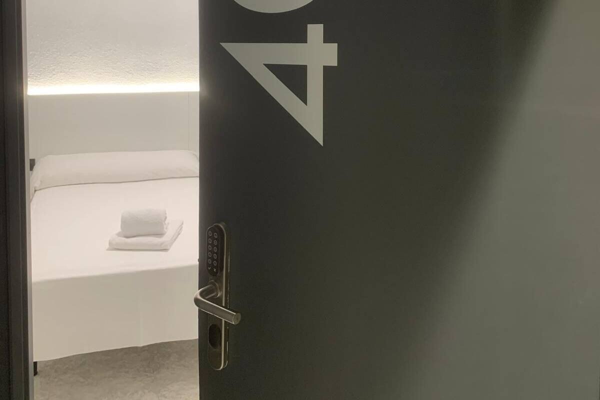 Une chambre avec un lit, une table de chevet et une porte portant le numéro 402.