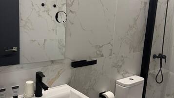 Un baño moderno con lavamanos, inodoro y ducha blancos.
