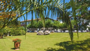 A well-maintained lawn with outdoor seating and a building with balconies in the background. - Jardins de Bakea (Biriatou)