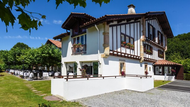 A two-story building with a white facade, wooden balconies, and flower boxes. - Jardins de Bakea (Biriatou)