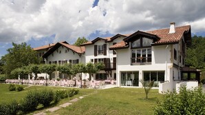 A large, multi-story building with a white facade and red-tiled roofs, featuring balconies and large windows. - Jardins de Bakea (Biriatou)