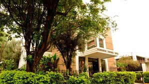 A hotel with a covered entrance, surrounded by lush greenery and a well-maintained hedge. - Hotel Pantanal Chácara Klabin (São Paulo)