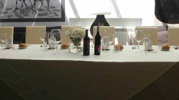 Una mesa de comedor lista con copas de vino, una botella y un jarrón con flores.