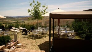 An outdoor seating area with tables and chairs, a tree, and a view of the countryside. - Hospedium Hotel Convento Santa Ana (Atienza)