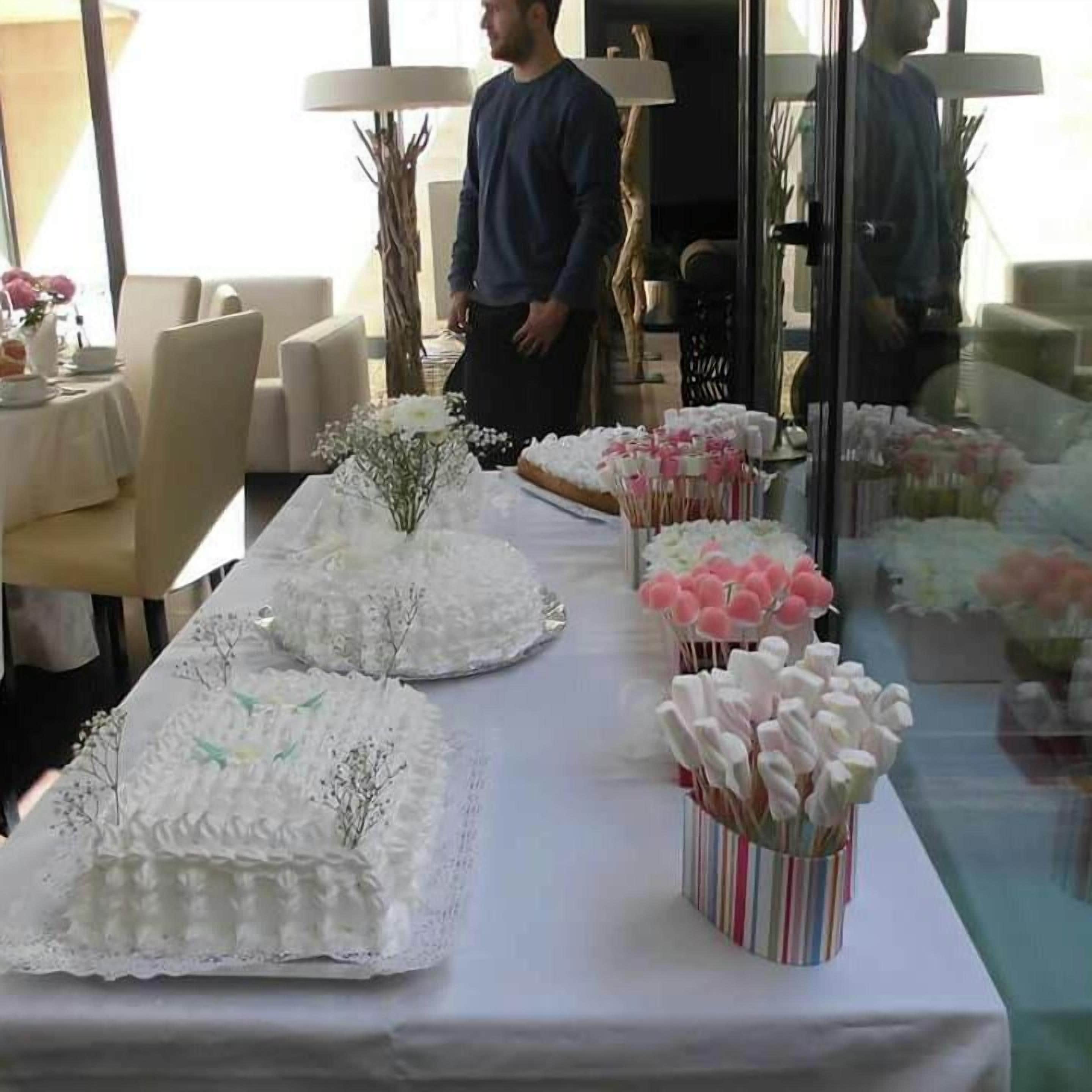 A long table with white tablecloths, floral centerpieces, and pink and white decorative items.