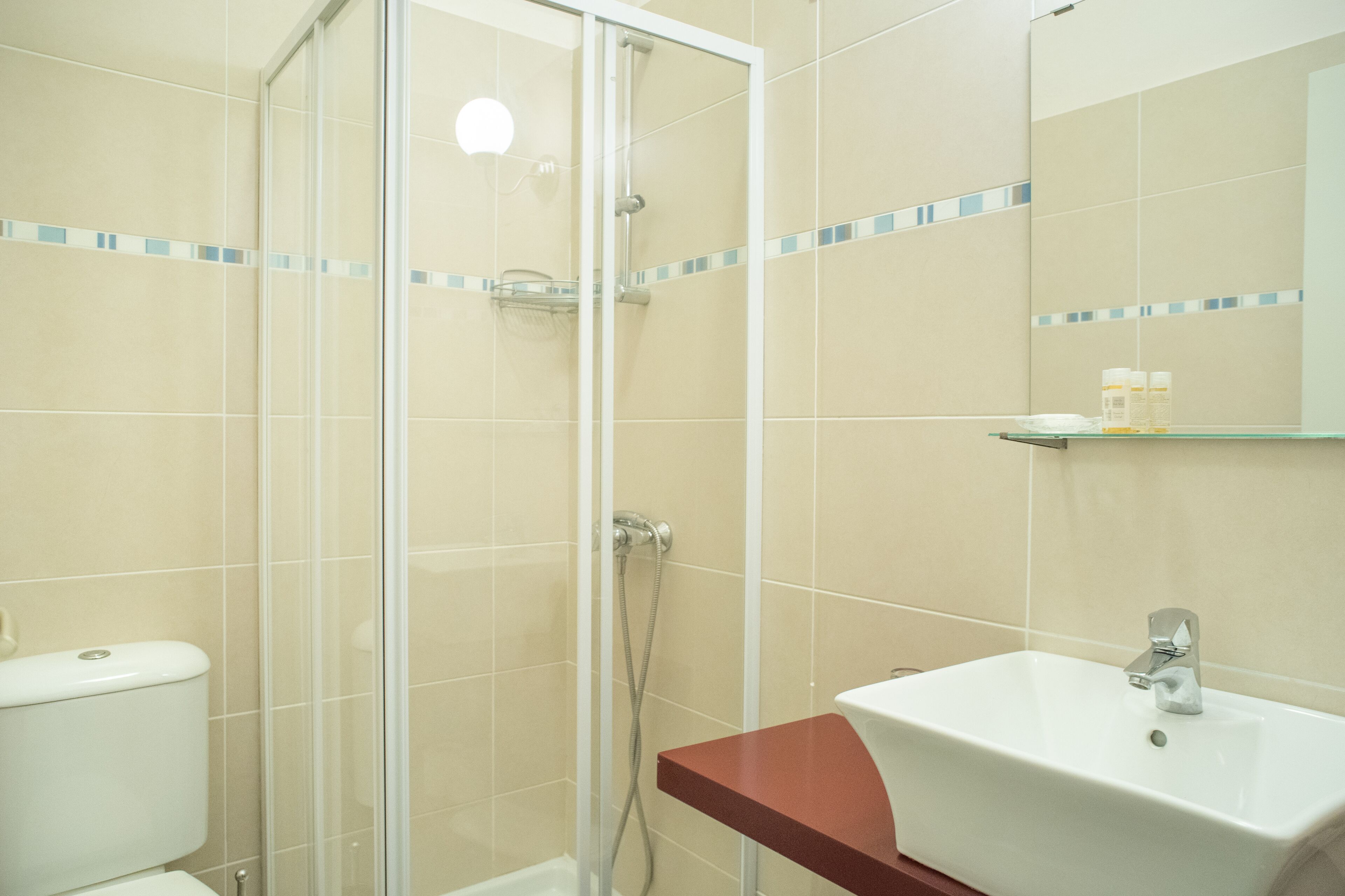 A bathroom with a glass-enclosed shower, a white sink, and a mirror above it.