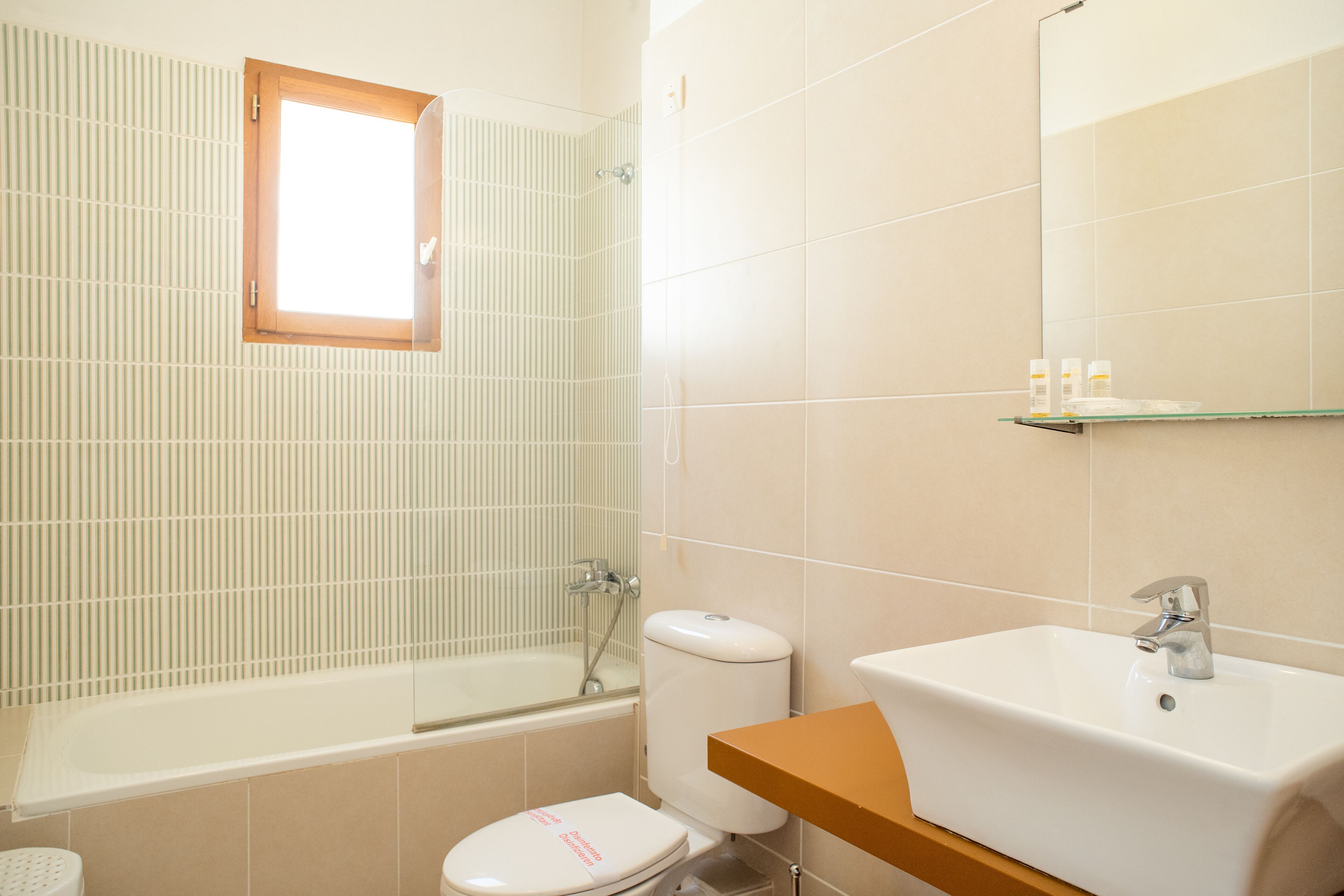 A bathroom with a bathtub, toilet, sink, and a window.