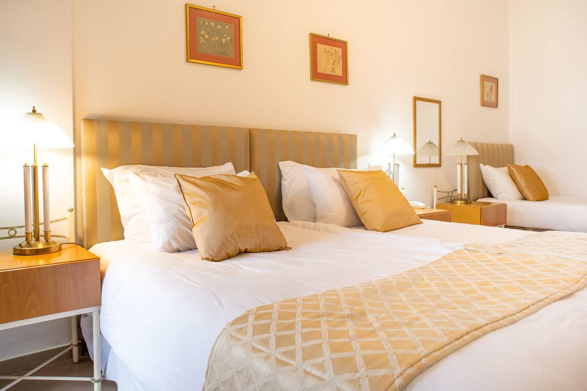 A hotel room with a large bed, two bedside tables, and a nightstand.