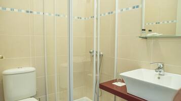 A bathroom with a glass-enclosed shower, a white sink, and a toilet.