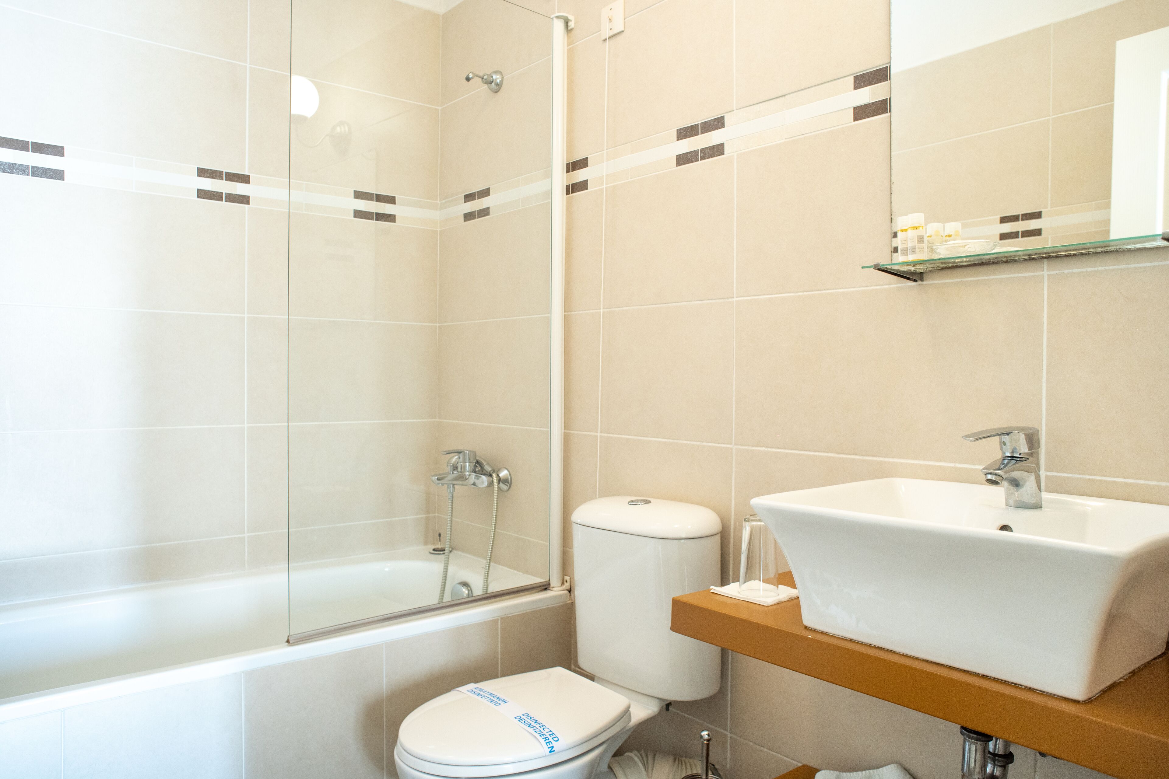 Een moderne badkamer met een douche met glazen wand, een wit toilet en een wastafel met spiegel erboven.