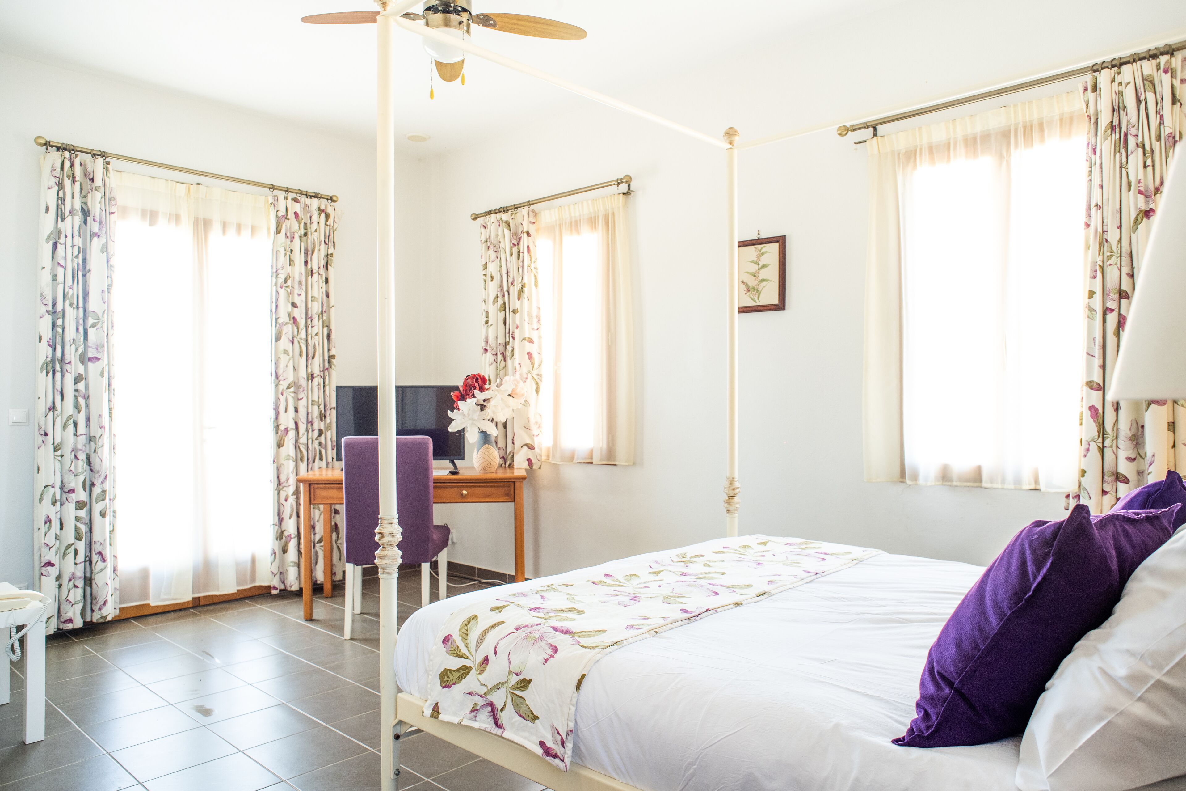 A bedroom with a bed, a desk, a chair, and a ceiling fan.