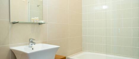 A bathroom with a white sink, mirror, and bathtub.