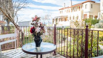 A round table with a vase of flowers on a balcony with a metal railing.