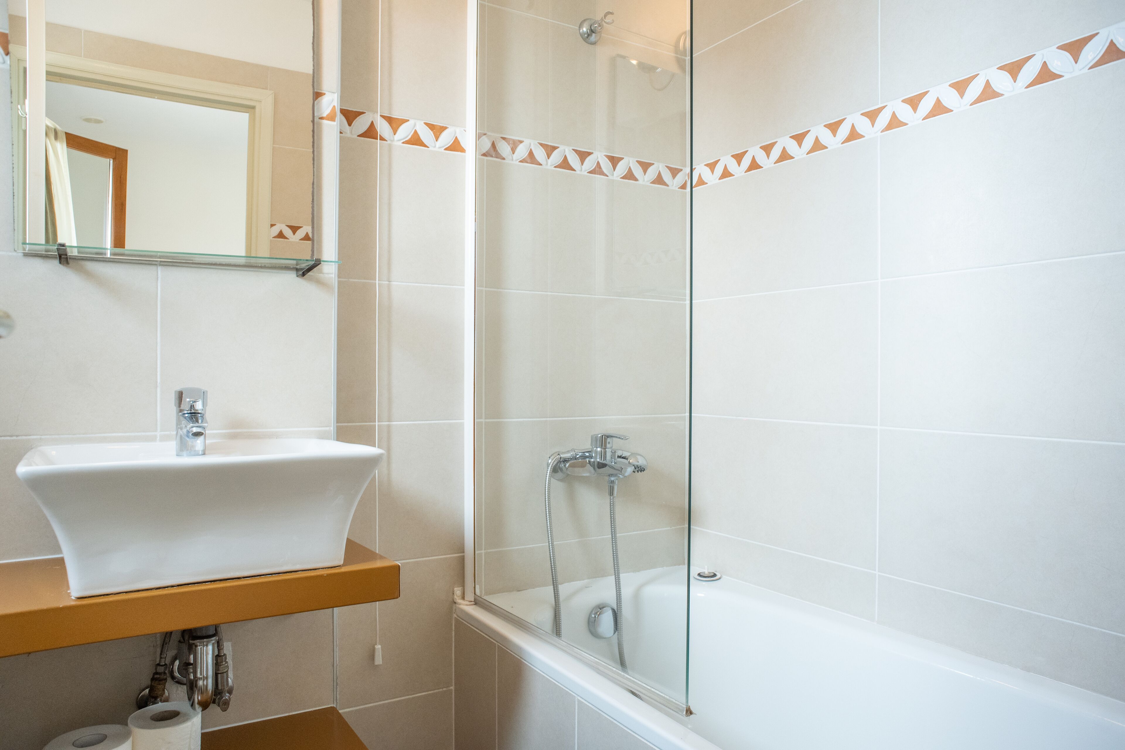 Un baño con lavamanos blanco, cabina de ducha con paredes de vidrio y bañera.