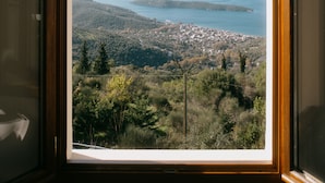 Ein Fenster mit Blick auf einen See, umliegende Hügel und eine kleine Stadt.