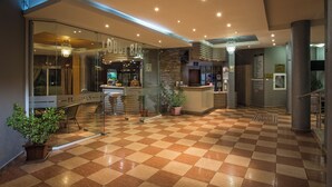 Un hall d’hôtel avec un sol à carreaux, un comptoir de réception et un espace bar.