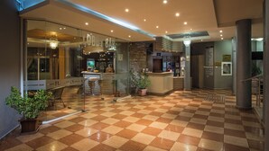 Un vestíbulo de hotel con suelo a cuadros, una recepción y una zona de bar.