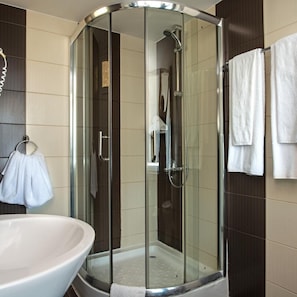 Un baño moderno con ducha de vidrio, lavabo blanco y toallero.