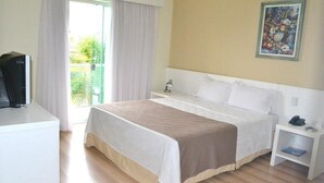 Een hotelkamer met een bed, nachtkastje met lamp, telefoon en een schilderij aan de muur.