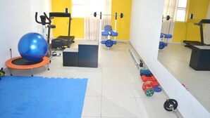 Een sportschool met trainingsapparatuur, een trampoline en een blauwe mat.