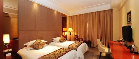 A hotel room with two beds, a desk, a chair, a television, and a large window with curtains.