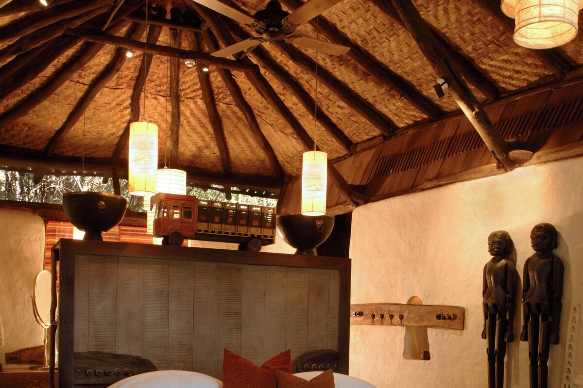 A spacious bedroom with a large bed, a wooden headboard, and a bench at the foot of the bed.