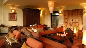 A cozy living room with orange sofas, a wooden coffee table, and a large tree trunk as a centerpiece.