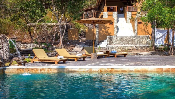 A pool area with lounge chairs and a stone pathway. - Nusabay Menjangan by WHM (Sumberklampok)